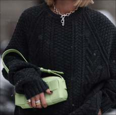 Nadine Berneis seen wearing Black Palms the label black wool cable knit sweater, silver earrings, Glambou silver chain necklace, Bottega Veneta light green / pastel green leather bag, on November 29, 2023 in Berlin, Germany. 