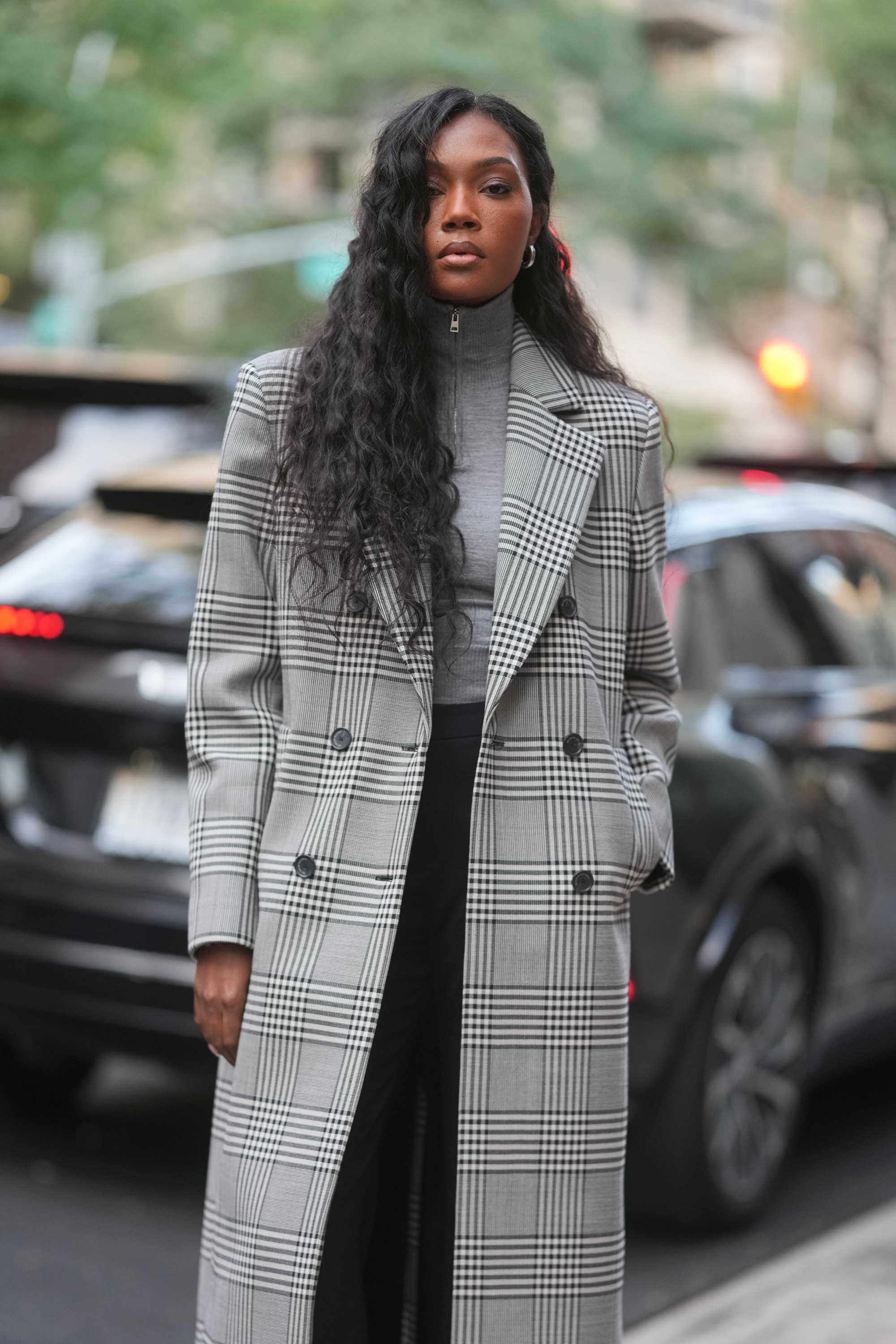 a woman with long dark hair wearing a black and white coat on the street during new york fashion week