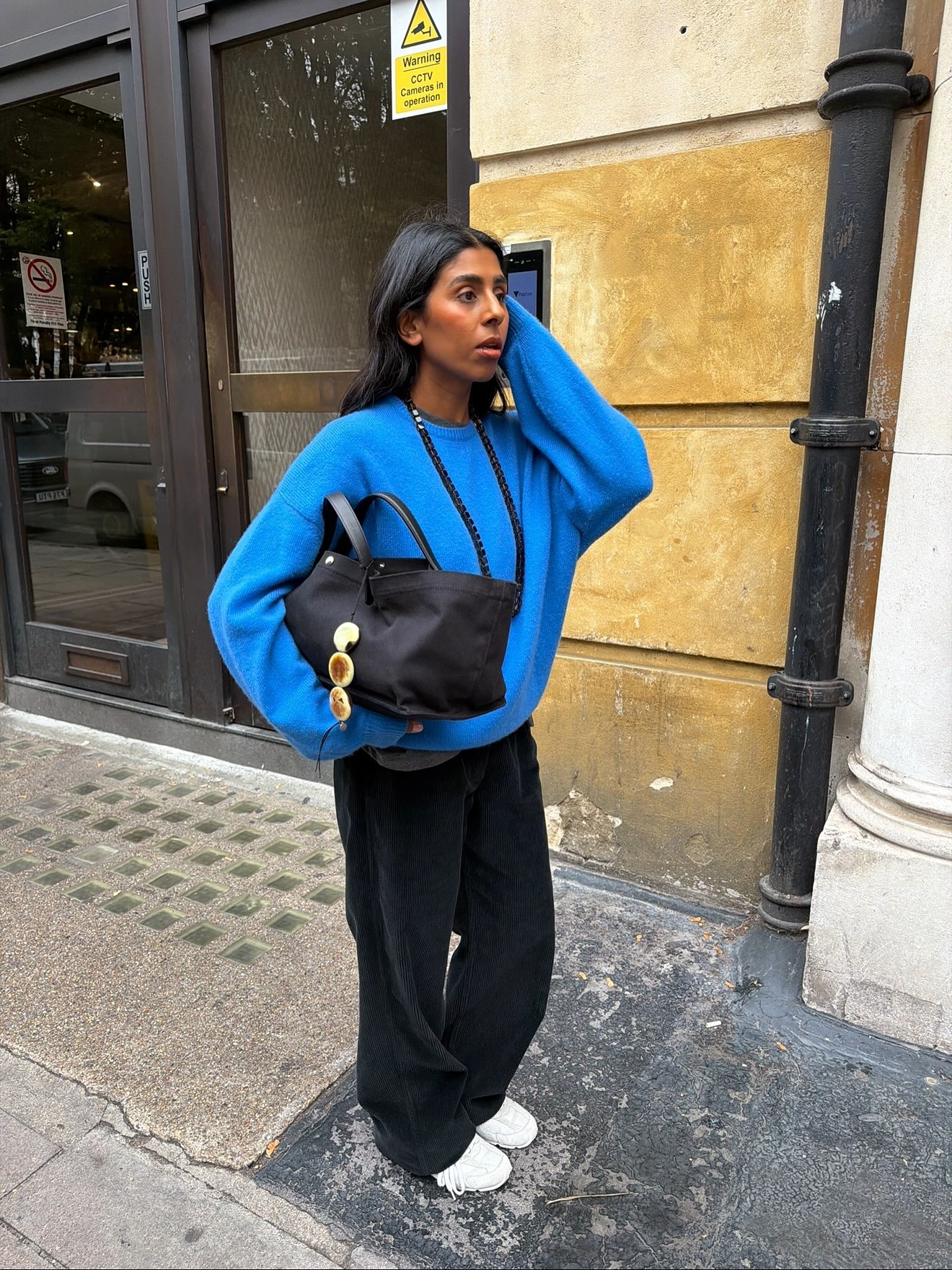 Influencer wearing a blue sweater, black pants, and white sneakers