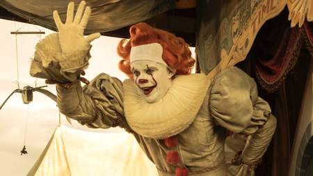 Human Pennywise (Bob Gray) in full clown makeup waves to onlookers from the stage during flashback in IT: Welcome to Derry Season 1