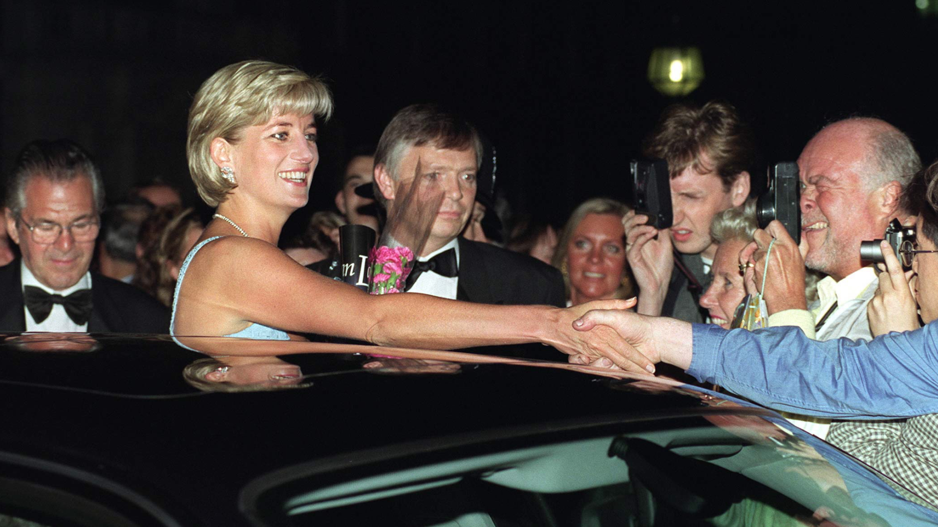 Princess Diana sticking her head out of a limo sunroof and shaking hands with fans in 1997
