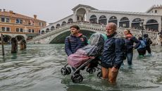 VENICE, ITALY - OCTOBER 29: Tourists carry a stroller through the flood waters on October 29, 2018 in Venice, Italy. Today due to the exceptional level of the "acqua alta" that reaced 156 cm 