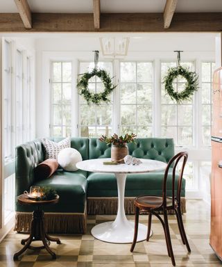 Dining area with green buttoned banquette seating and a round dining table