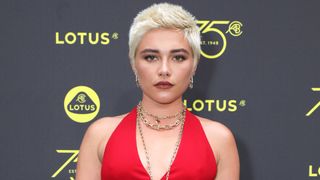Florence Pugh has blonde hair and wears a red jumpsuit as she attends the launch of Lotus London, the first flagship in Europe for Lotus cars, on July 27, 2023 in London, England.