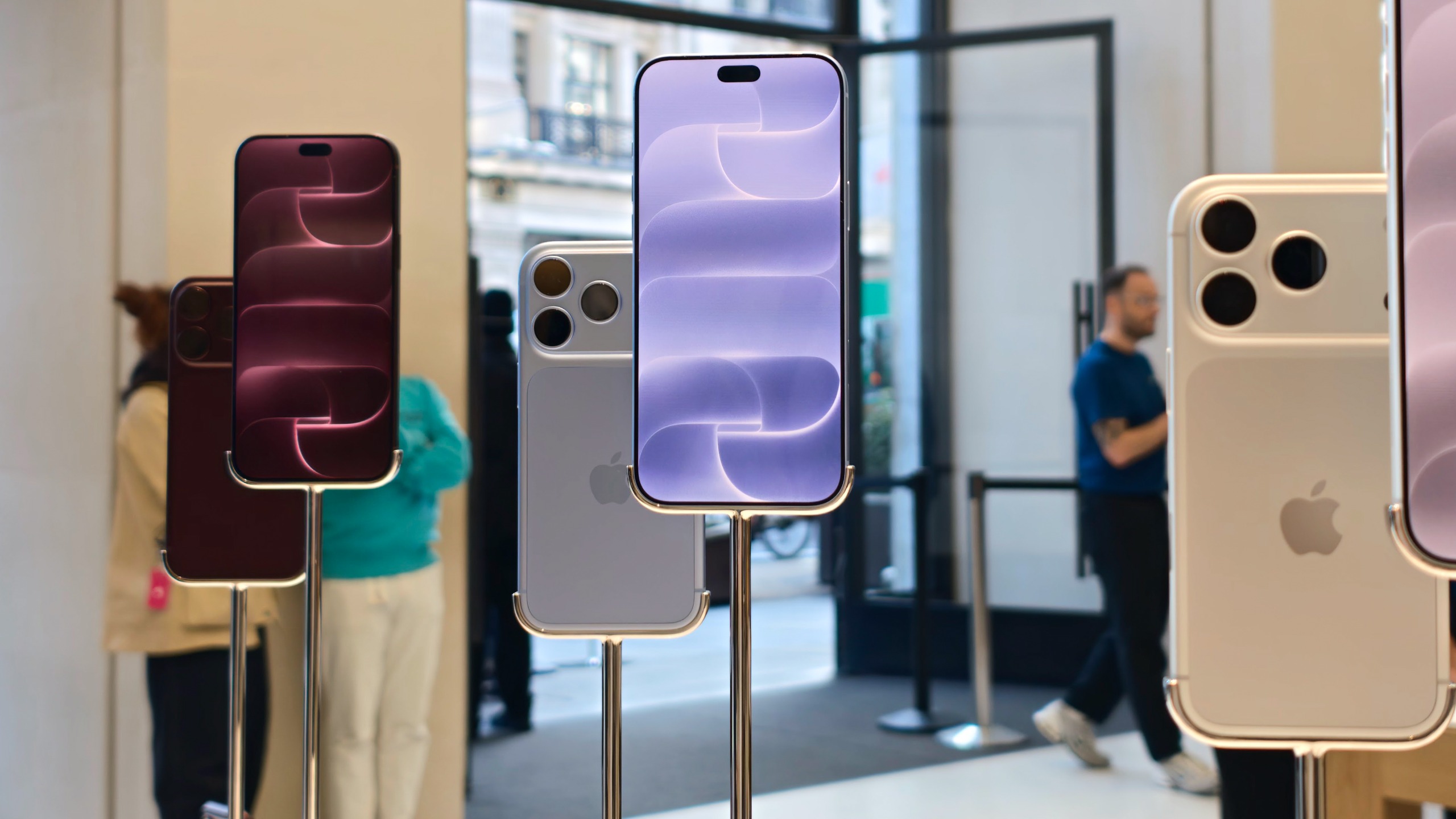 Burgundy and silver iPhone 18 Pro models displayed on metal stands inside an Apple Store.