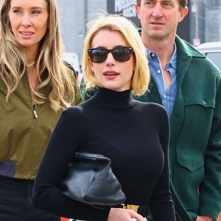 Emma Roberts wearing a black turtleneck, polka dot skirt, and black boots