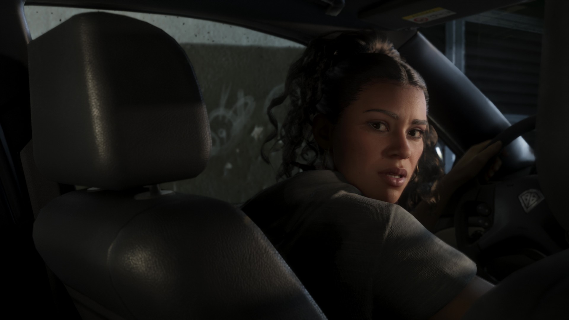 Lucia looks over her shoulder from the driving seat of a car, from the GTA 6 extended look