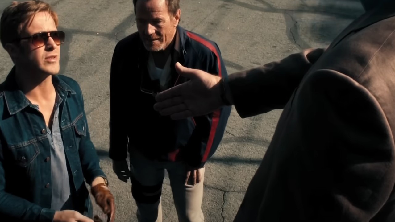 Ryan Gosling with Bryan Cranston as a hand is extended out in Drive