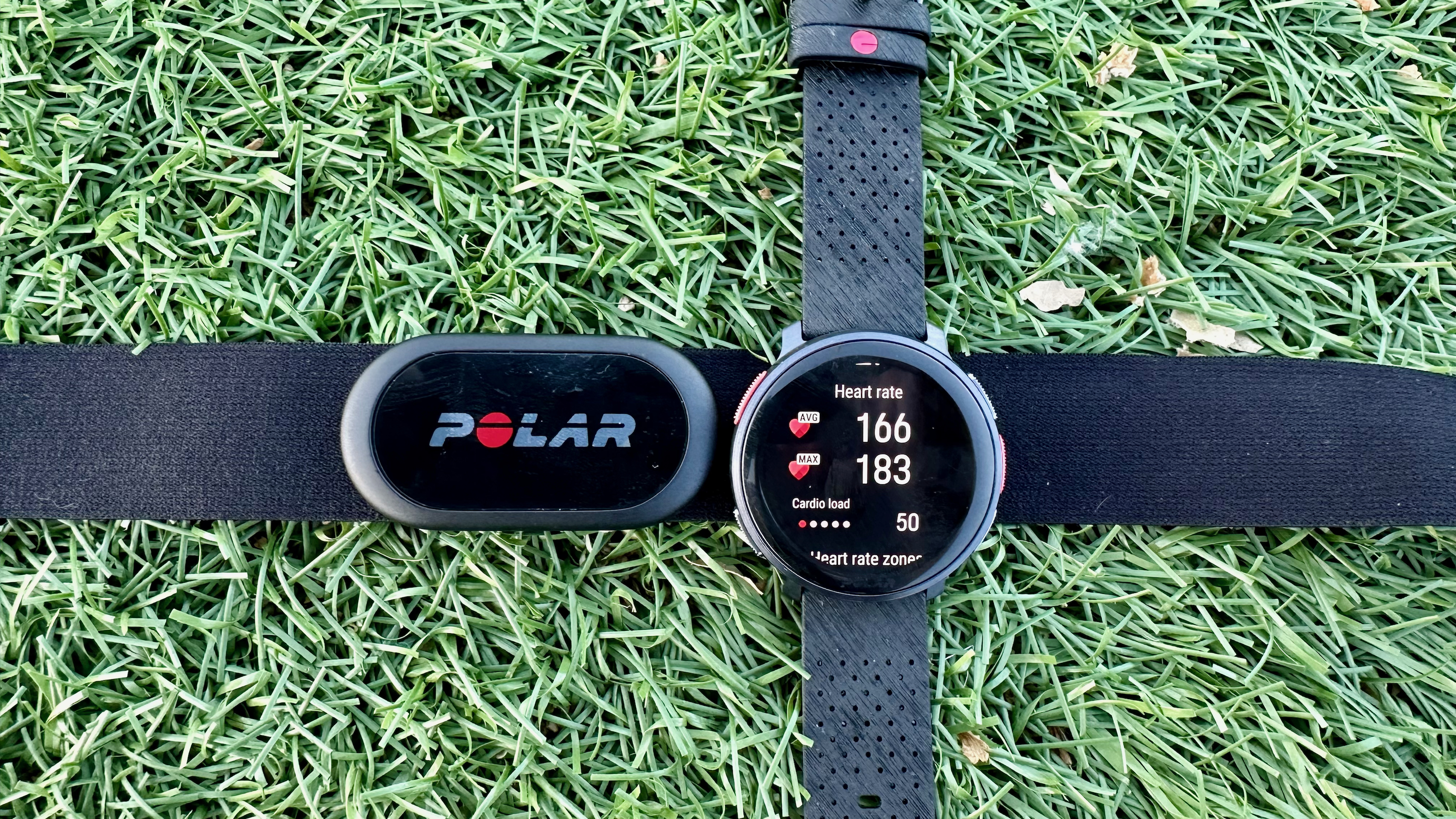 The Polar Vantage V3 and Polar H10 sitting on grass, with the watch showing the workout's average and max heart rate.