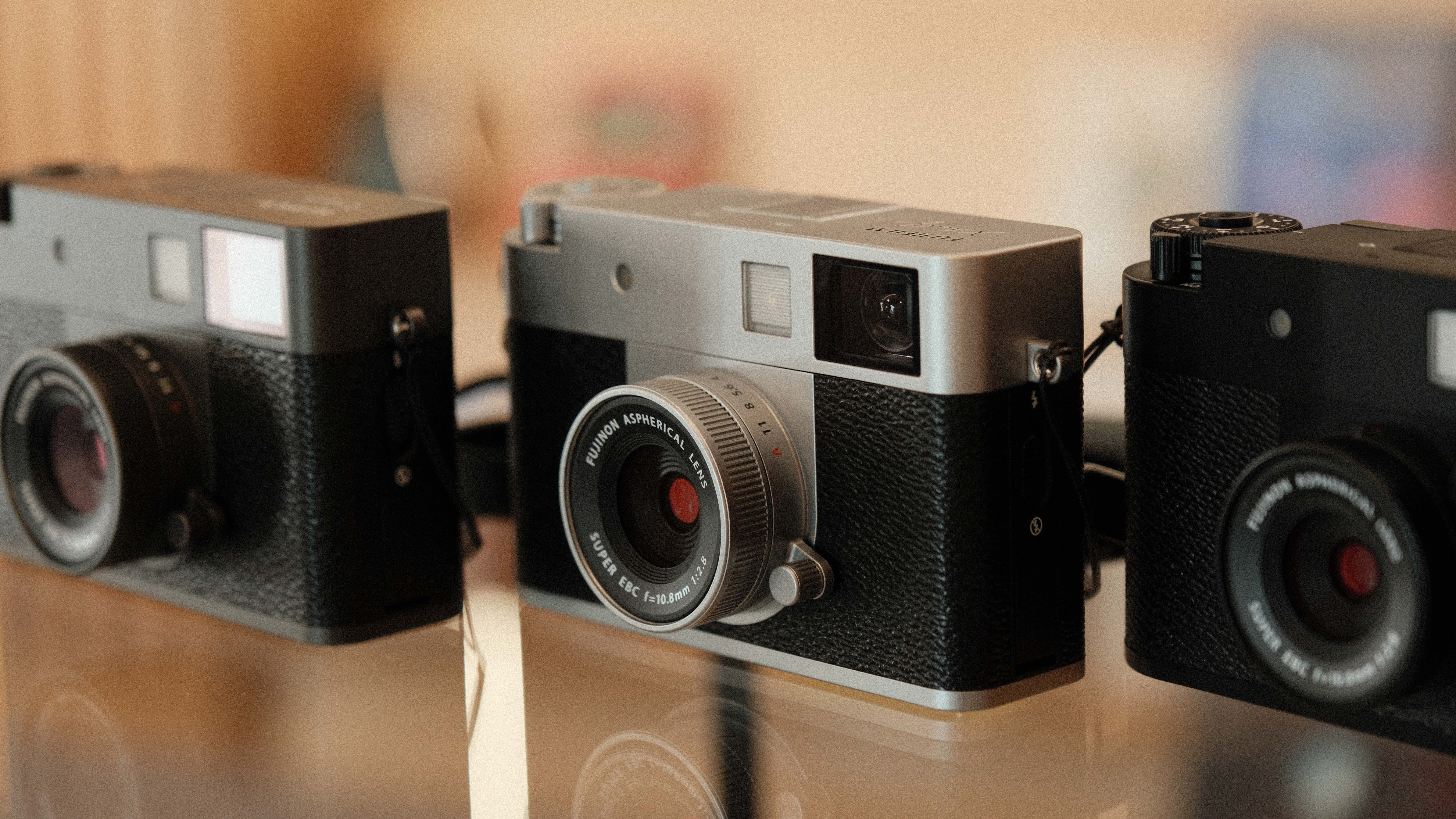 Fujifilm X Half camera in three colors next to one another on a glass table