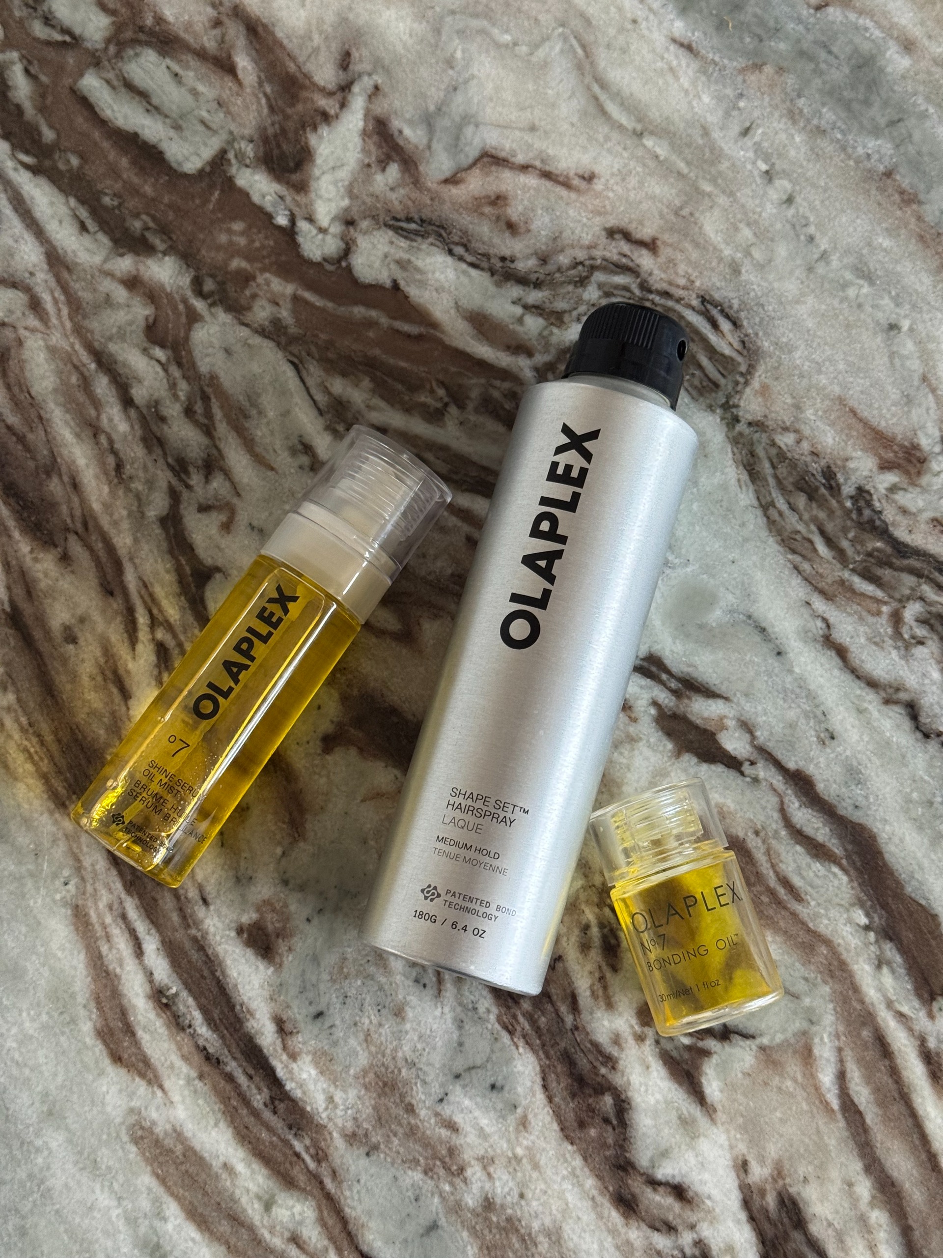 Three olaplex styling products on a marble table