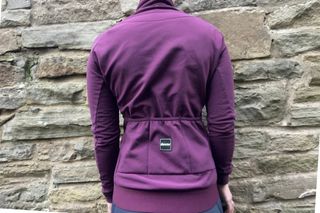 The Purple Santini RTR Winter Jacket shown from the back with a stone wall in the background