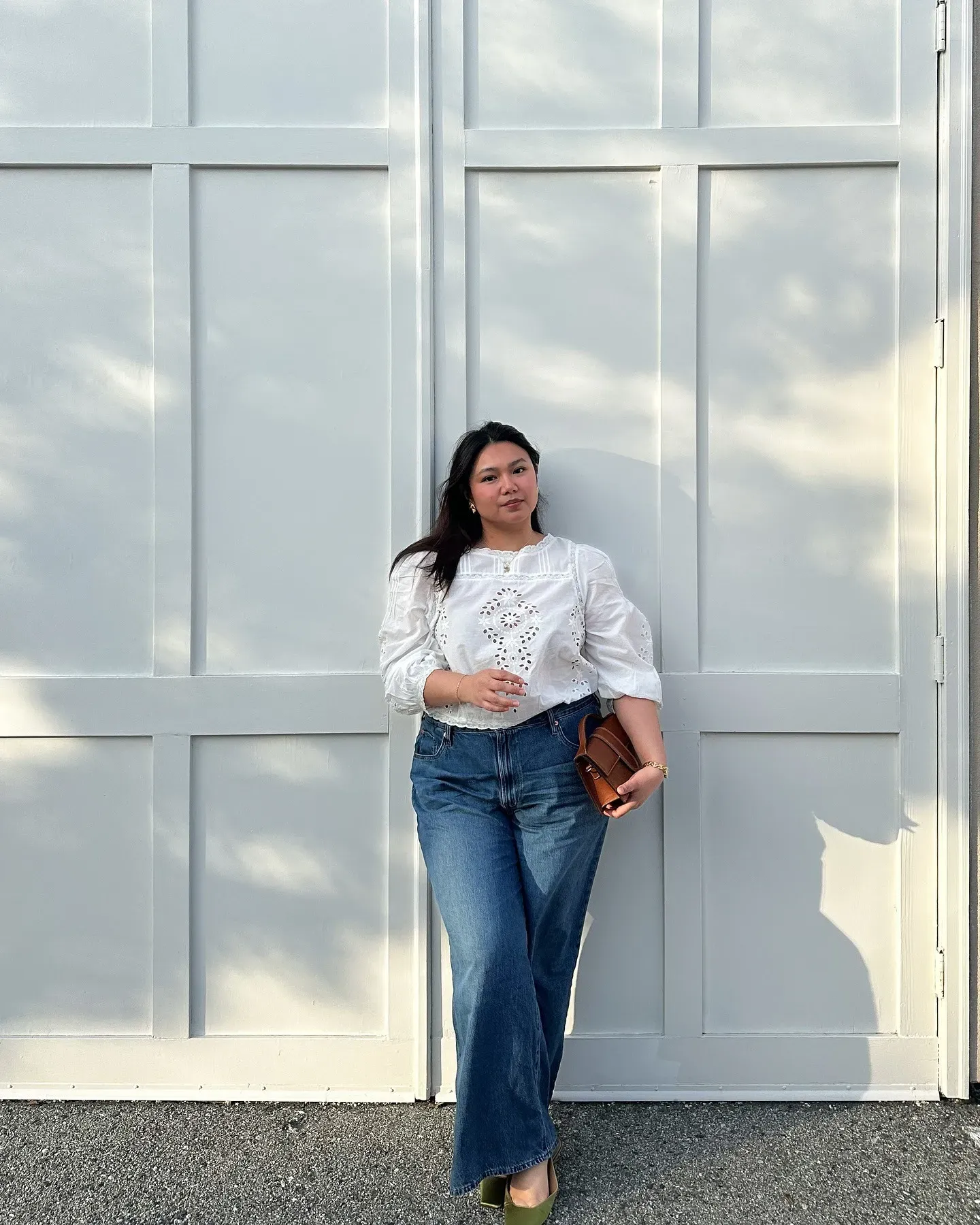 Marina wears pretty white lace blouse with wide blue jeans, green shoes and a brown leather handbag