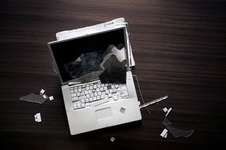 Laptop on a desk with a smashed screen and missing keys