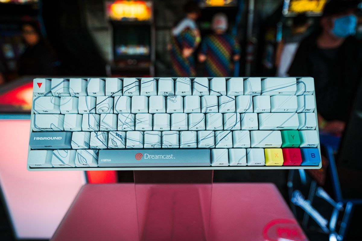 Overhead view of largely white, Dreamcast themed keyboard with system diagram and colorful face button arrow keys.