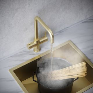 gold tap poring boiling water into a pot with spaghetti inside