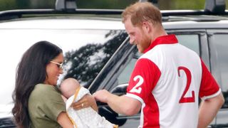 Prince Harry and Meghan Markle smiling at a baby Archie