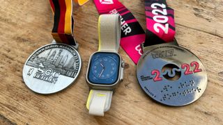 Berlin Marathon medal, Apple Watch Ultra, London Marathon medal in a line