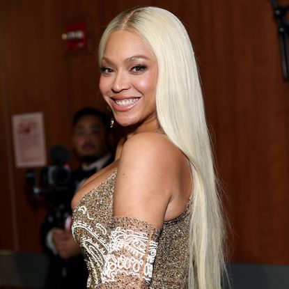 Beyonce with platinum blonde hair smiling over her shoulder at the camera. 