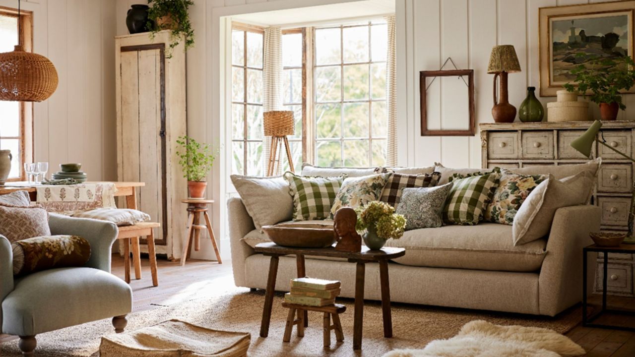 A living room with white wall paneling, a gray couch with green cushions, a wooden coffee table, and a gray armchair