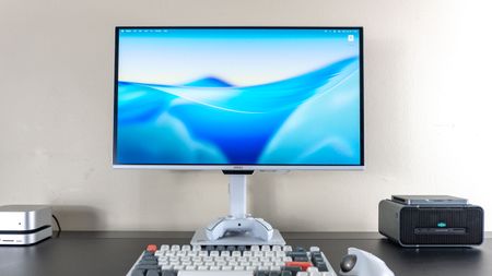 A desk setup built around the MSI Pro Max 271UPXW12G monitor with a Mac mini M4 on the left and a mini PC on top of an eGPU on the right