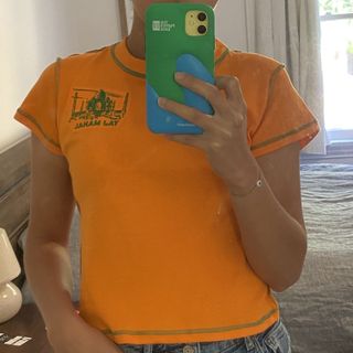 Woman taking a selfie in a bright orange T-shirt.