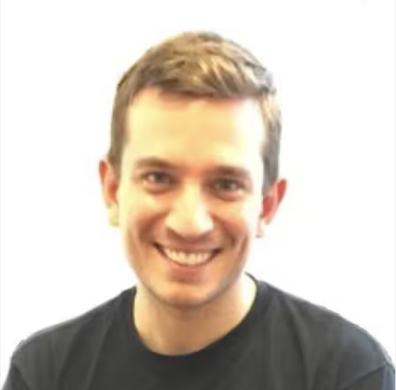 Headshot of Adam Hamilton smiling and wearing a black t-shirt against white background.