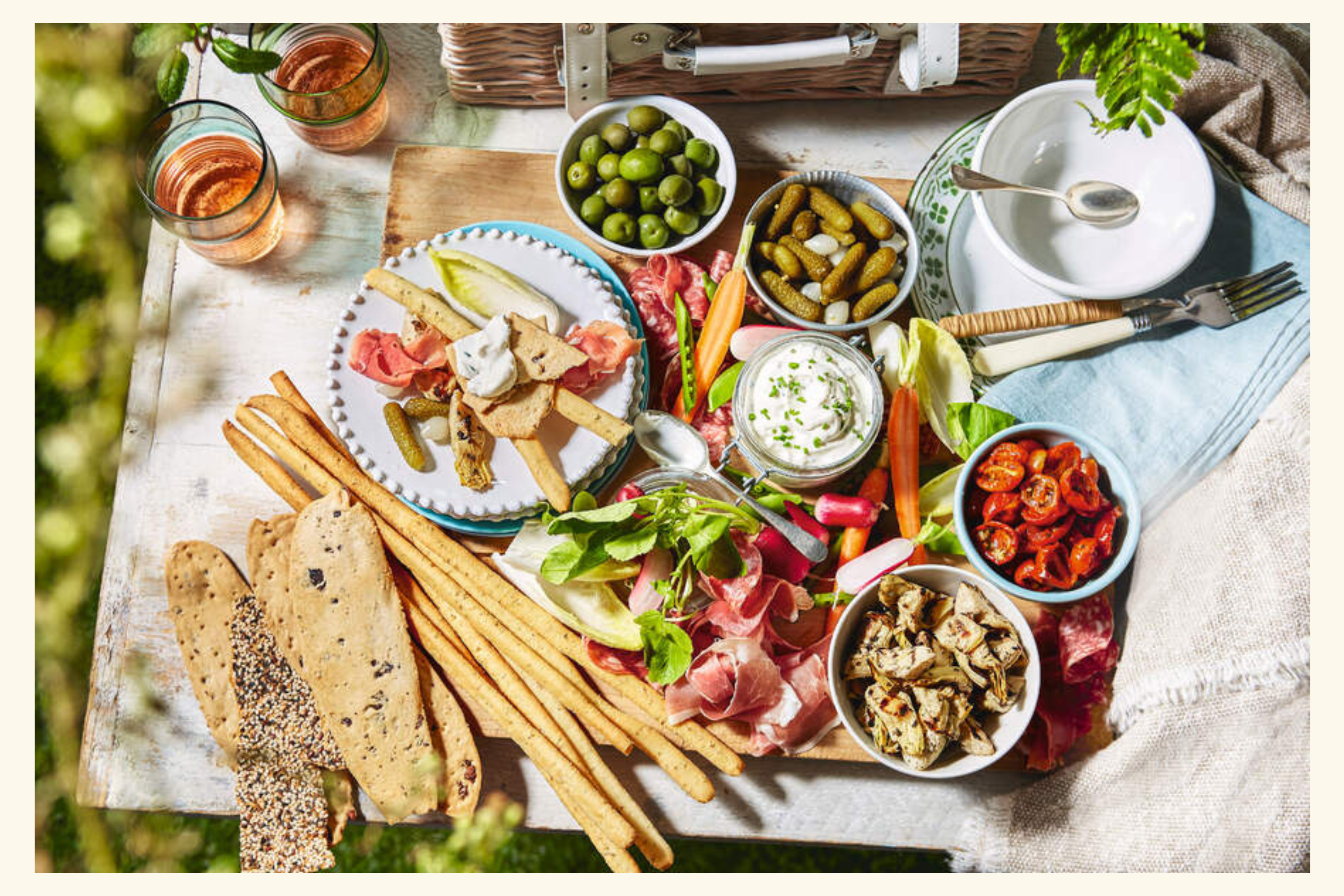 A beautifully arranged antipasti platter featuring cured meats, olives, pickles, fresh vegetables, and dips, perfect for a posh picnic.