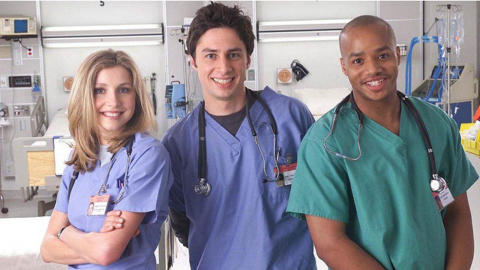 Zach Braff, Donald Faison and Sarah Chalke standing in front of a hospital bed in Scrubs