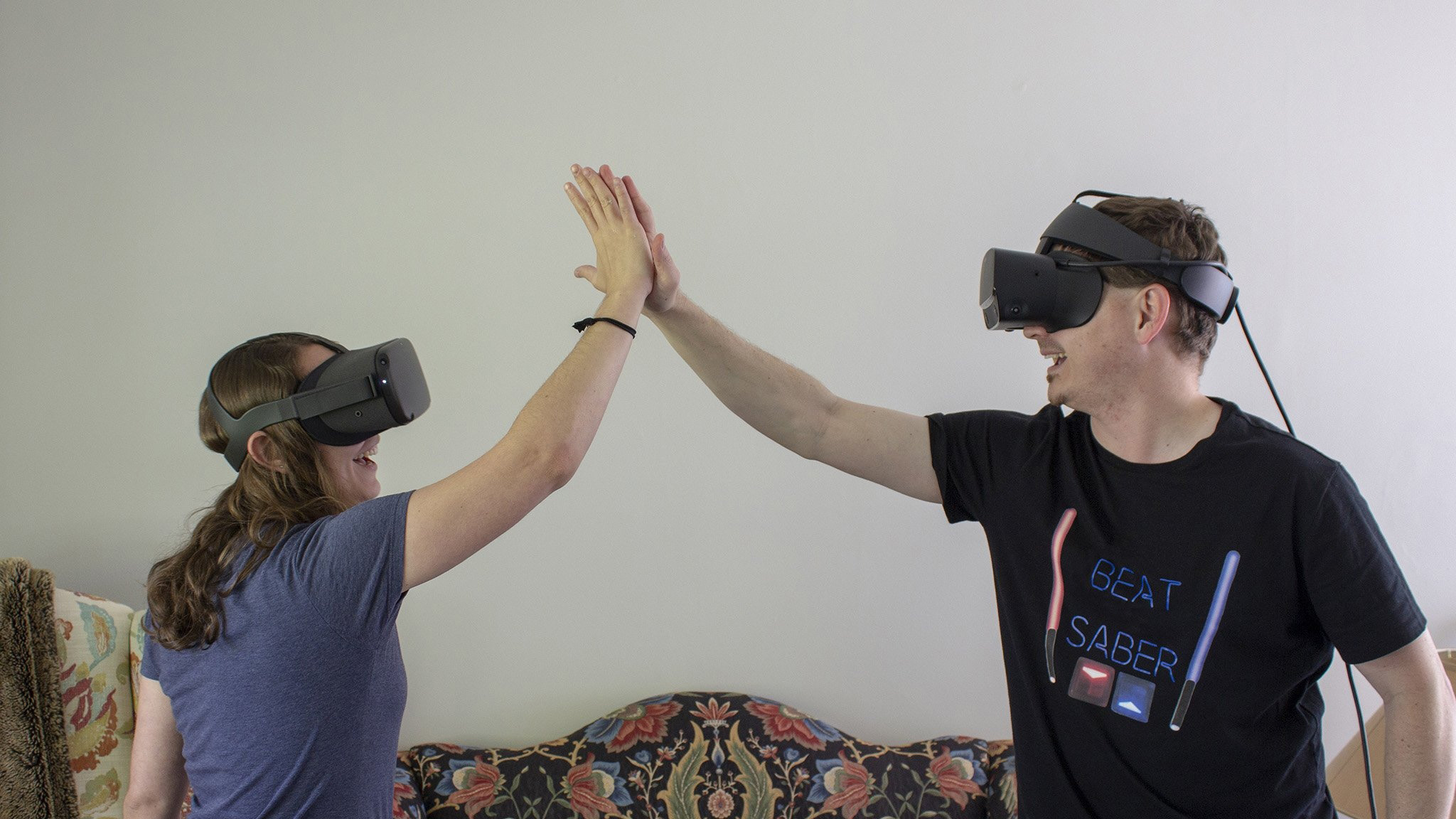 Two VR players high fiving each other while wearing an Oculus Quest and a Rift S
