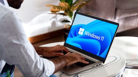 A man typing on a Windows 11 laptop