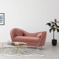 showroom with white wall and pink couch with potted plant