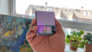 En mand med en lyserød Samsung Galaxy Z Flip 3, der er lukket, med det eksterne kamera aktiveret.
