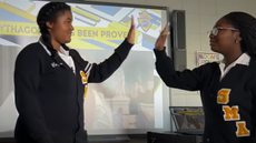 The two high school students high five each other.
