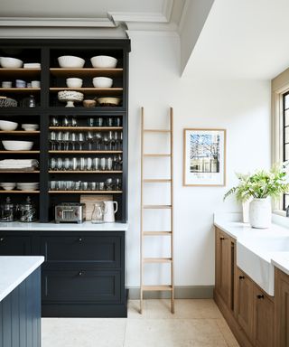 Black and white kitchen color ideas with a freestanding black painted cabinet, stone flooring and white walls.