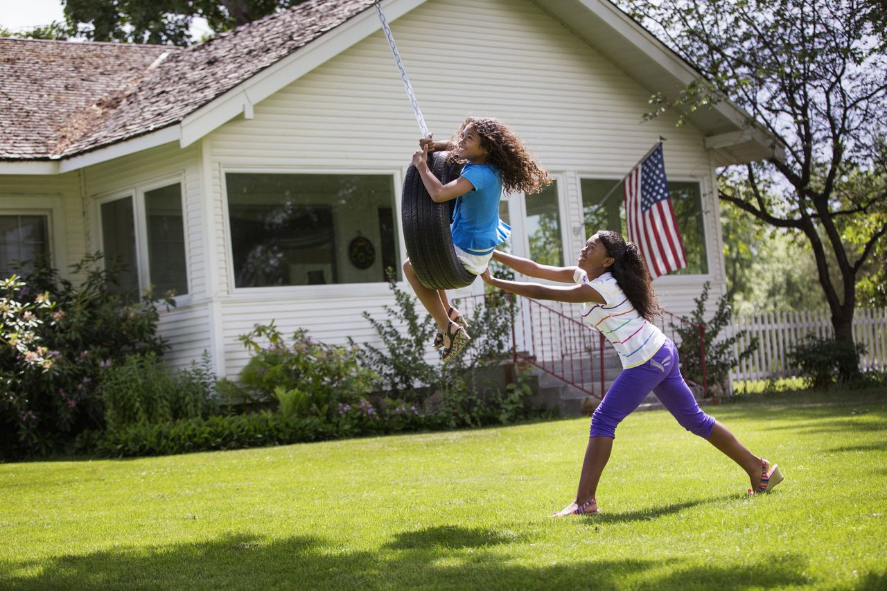 Mixed race girls playing on tire swing