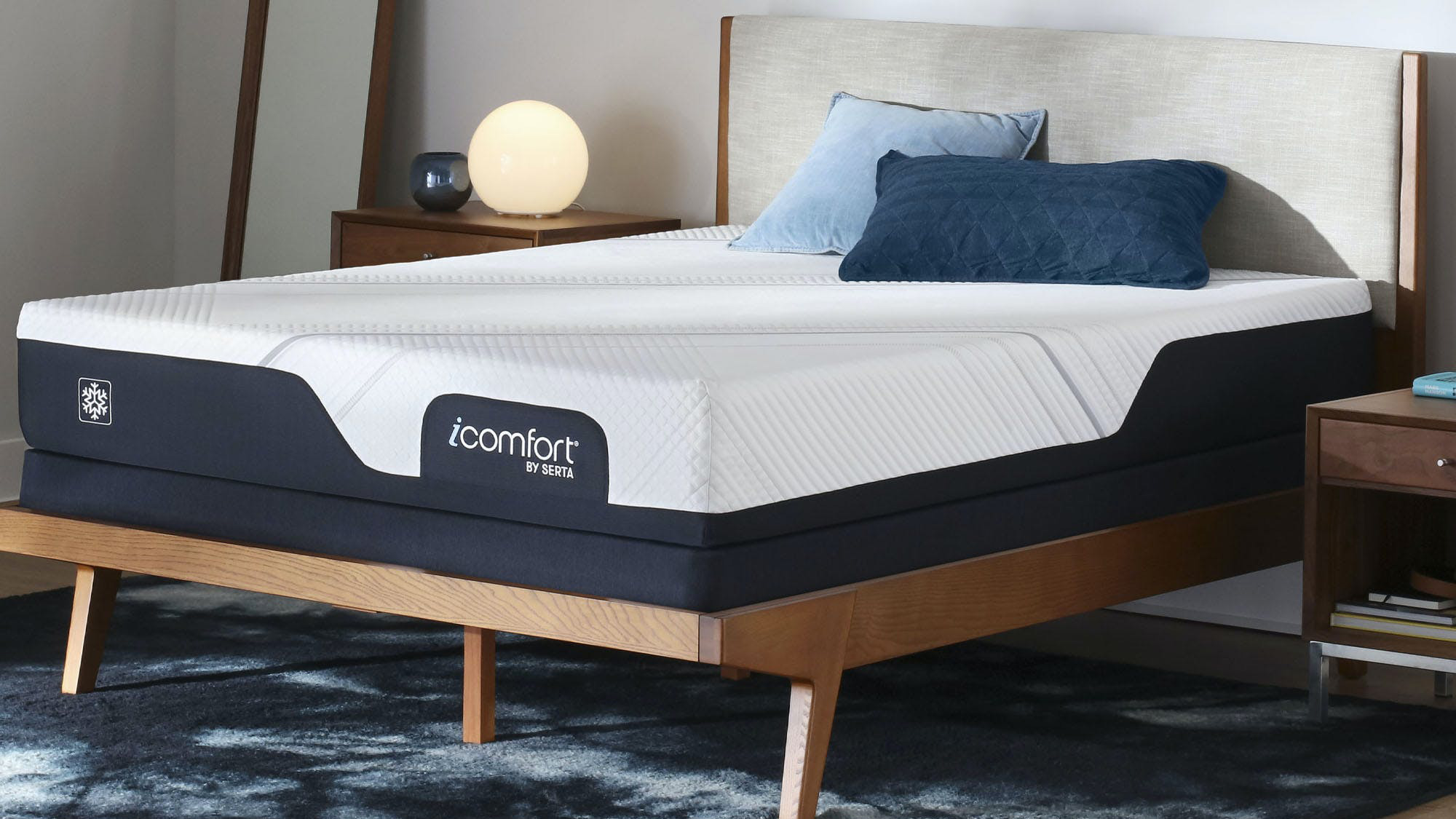 The Serta iComfort Mattress on a wooden bed frame and dressed with two blue pillows