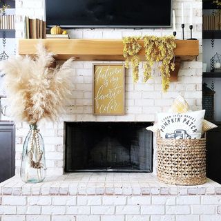 white washed brick mantelpiece with glass vase, pampas grass, a basket and fall foliage