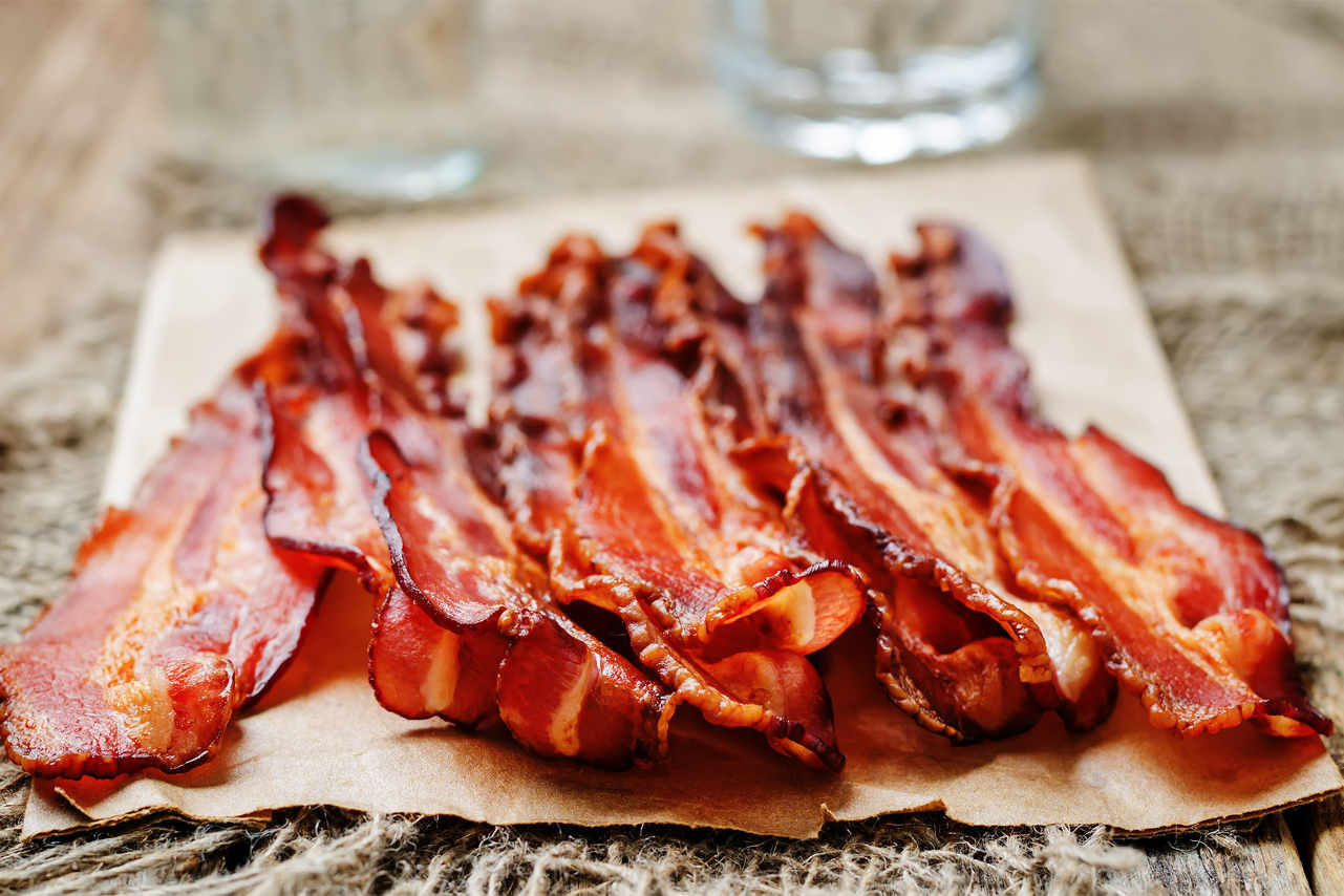 Pile of broiled bacon slices draining on towel 