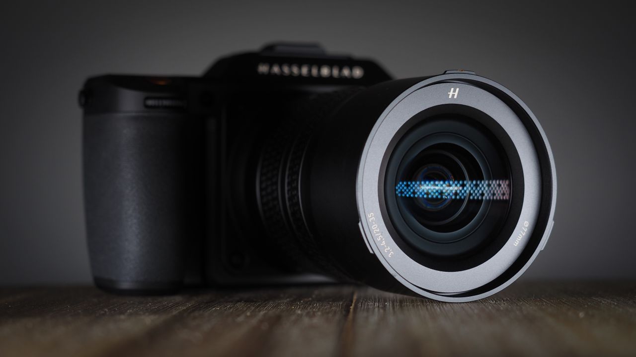 Hasselblad XCD 20-35E lens, moodily lit with subdued lighting, on a wooden surface