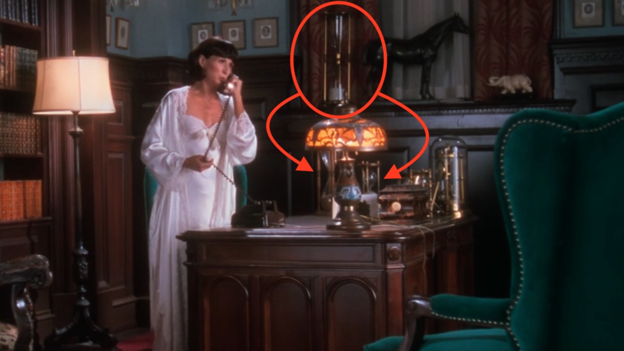 Mrs. Shirley talking on the phone. Red circle and arrows pointing out the hourglasses in the office in Christmas Vacation