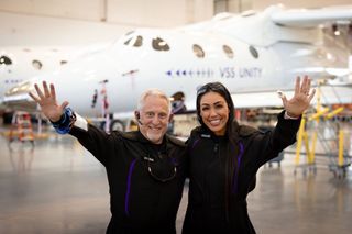 a man and woman wave in front of a space plane
