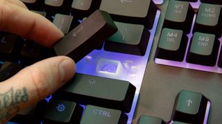 Person placing a keycap back onto a keyboard's key switch