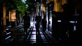 people walk down a dark street carrying flashlights