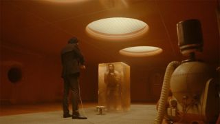 Image from the Marvel T.V. show Loki, season 2 episode 2. A man is trapped in a clear rectangular blob. Standing in front of him is a man in a dark suit.