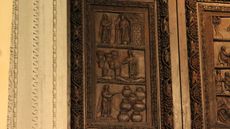 A wooden door at the Santa Sabina Church in Rome shows Jesus with a &ldquo;wand" performing miracles: (top to bottom) Jesus raising Lazarus; Jesus multiplying loaves and fish; Jesus turning water into wine. 