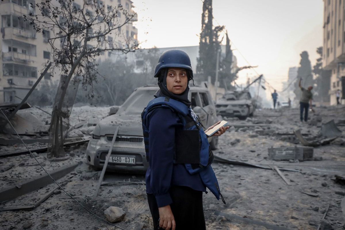 Samar Abu Elouf standing in press kit with a bomb site behind her 