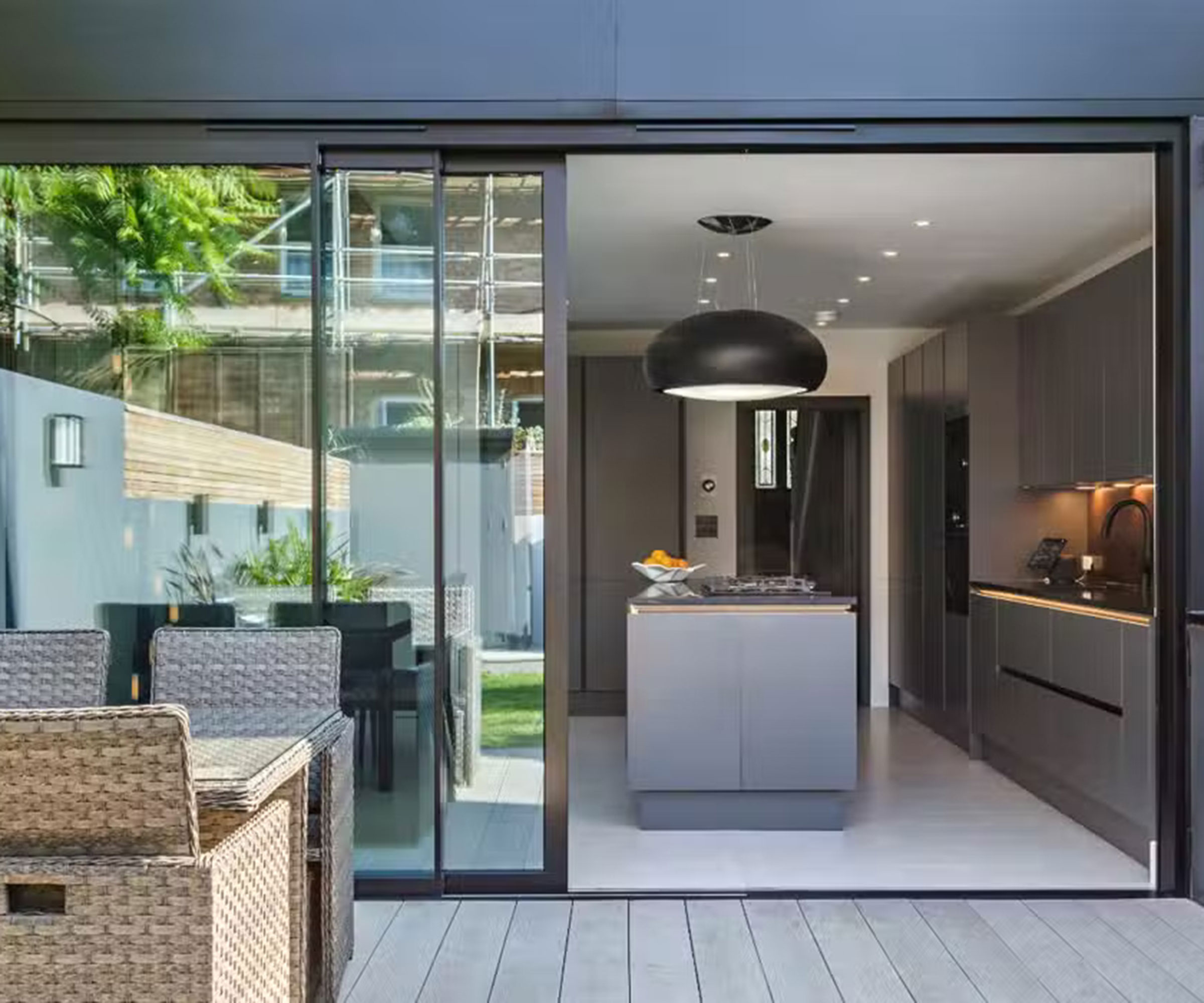 looking into a modern kitchen space through sliding doors from a decked patio