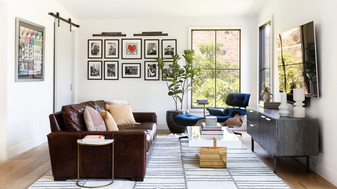 Living room with brown sofa fringed rug copper coffee table and blue chair by window with view