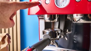 a red smeg espresso machine with burr grinder is photographed against a blue background